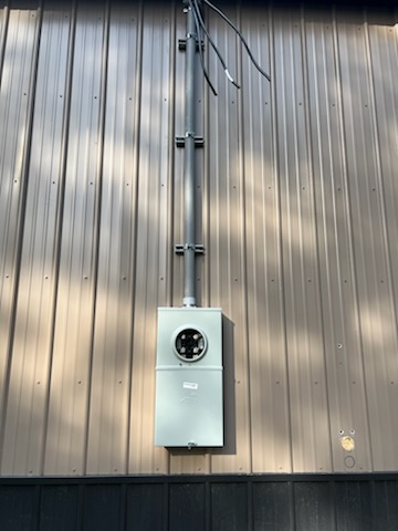 Meter and service entrance run installed on the exterior of a small metal-clad commercial building